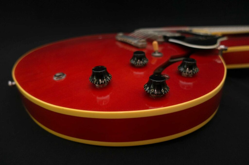 Top-down studio shot of a cherry-red Gibson semi-hollow body with cream binding on black.