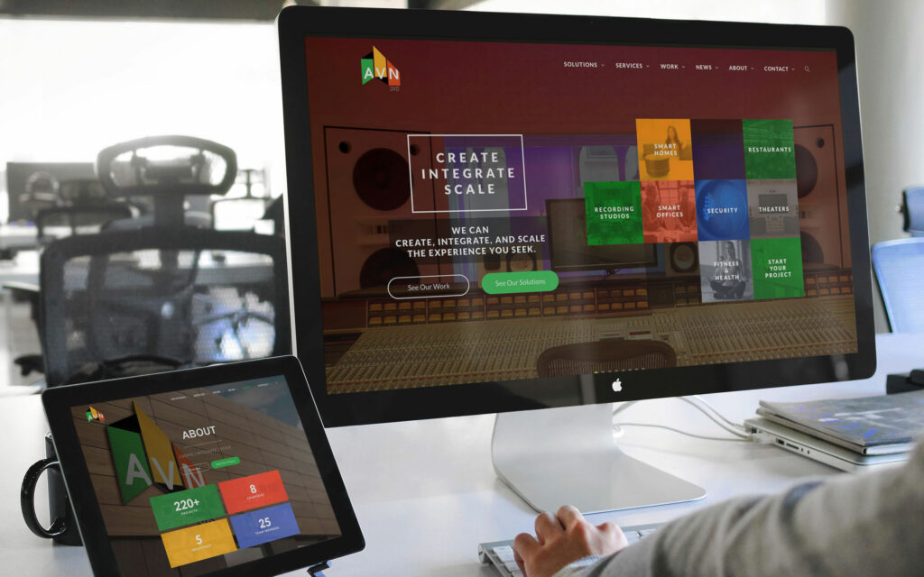 Desktop homepage with Create Integrate Scale headline over a studio hero, solution tiles at right and the About page on a tablet.