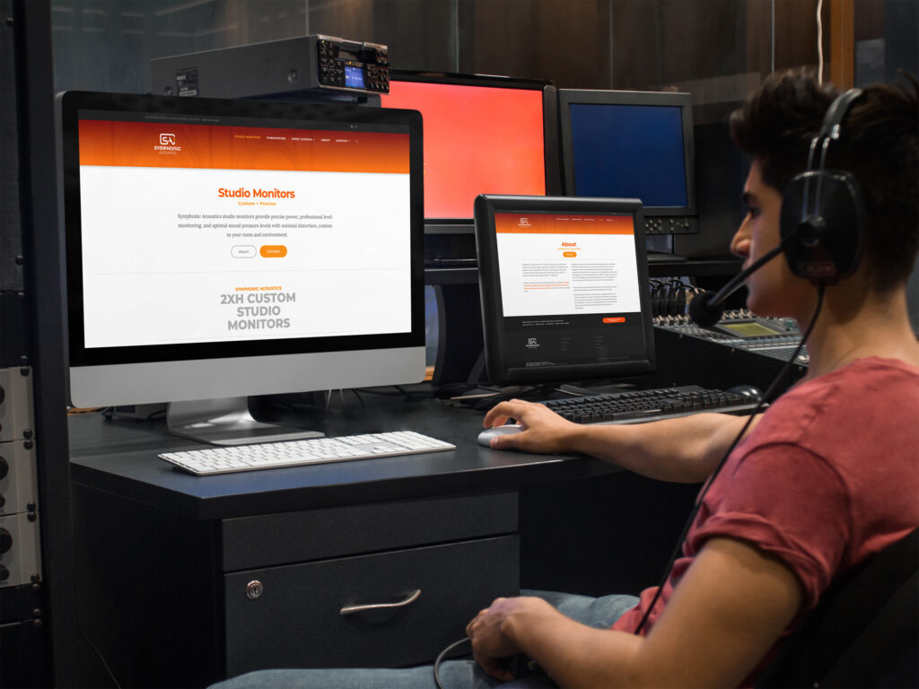 Engineer at a control desk viewing the Studio Monitors page on the main display with the About page on a second screen.
