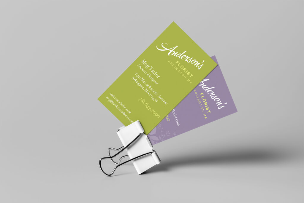 Green and lavender cards fanned in a binder clip, showing the contact side and the reversed script mark together.