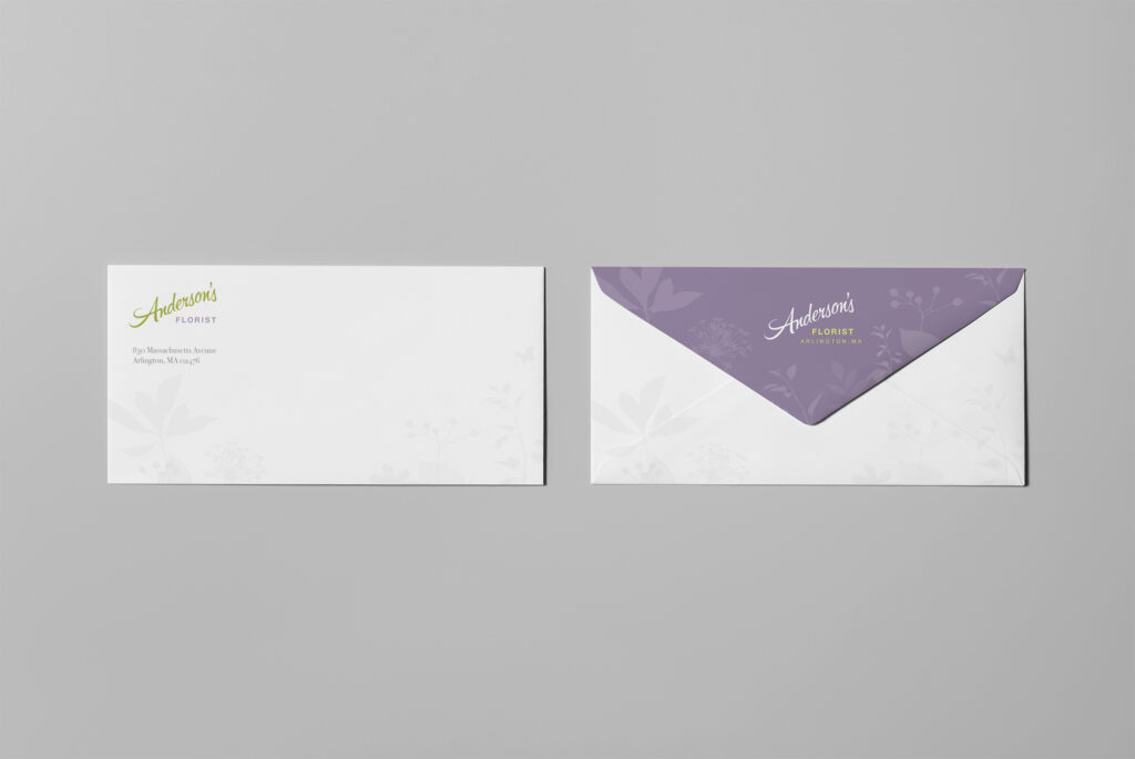 Number ten envelope pair showing the green script corner mark on the front and a lavender botanical flap on the reverse.