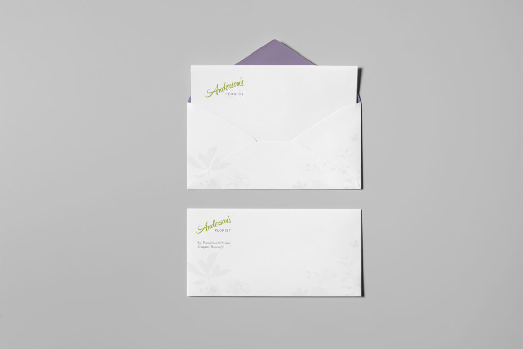 Open envelope revealing a lavender interior liner above a second sealed envelope, both carrying the green script corner mark.