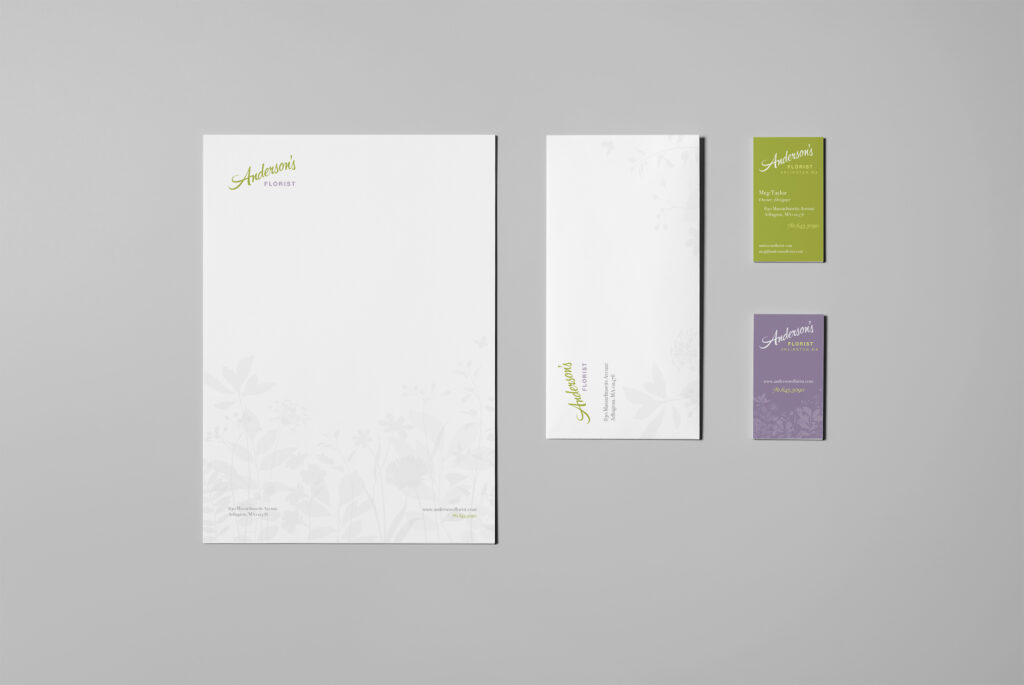 Letterhead, envelope, and green and lavender business cards arranged flat, the script mark repeating quietly across each piece.