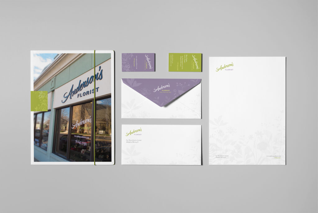 Complete suite beside a storefront-cover presentation folder: green and lavender cards, envelopes, and letterhead sharing one botanical system.