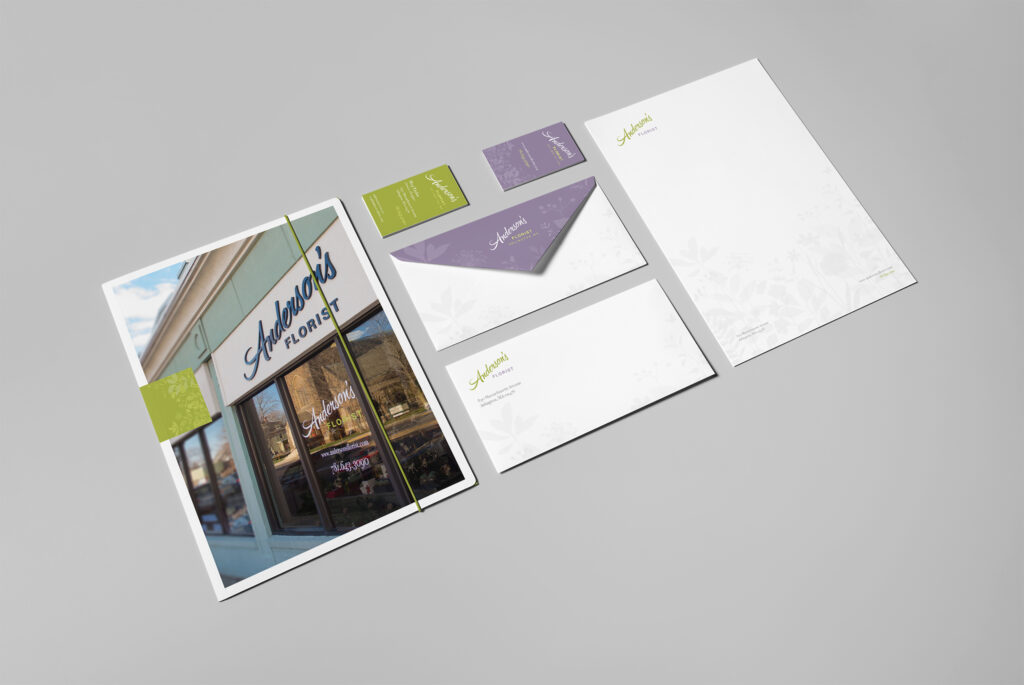 Angled view of the full suite with presentation folder, cards, envelopes, and letterhead receding across a gray field.