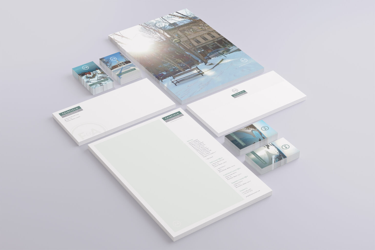 Stationery system in isometric view, the folder cover’s sunlit winter park scene above branded letterhead, envelopes, and photographic business cards.