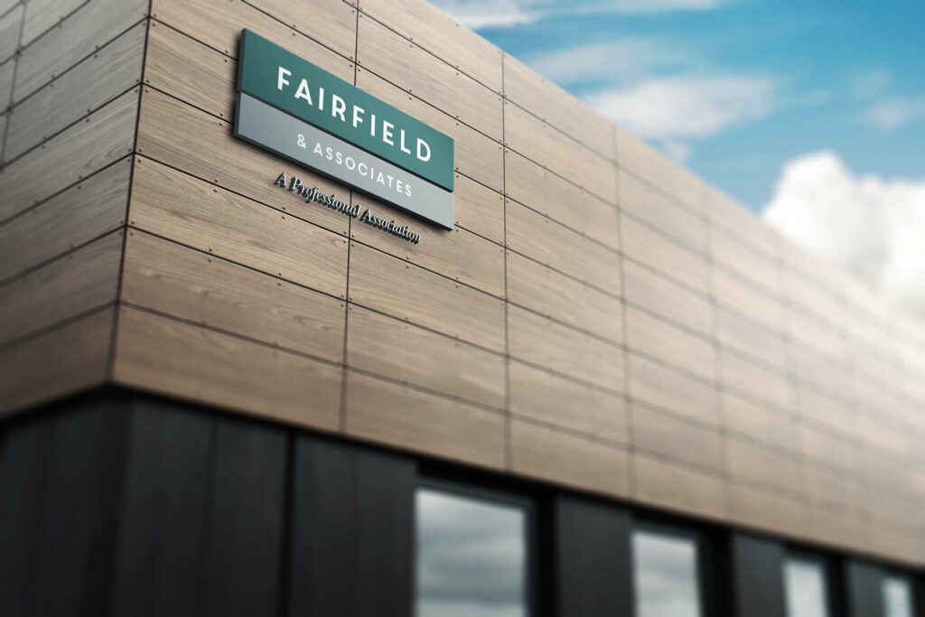 Fairfield & Associates dimensional sign in sea green and gray mounted on a modern wood-paneled facade beneath a scripted A Professional Association tagline.