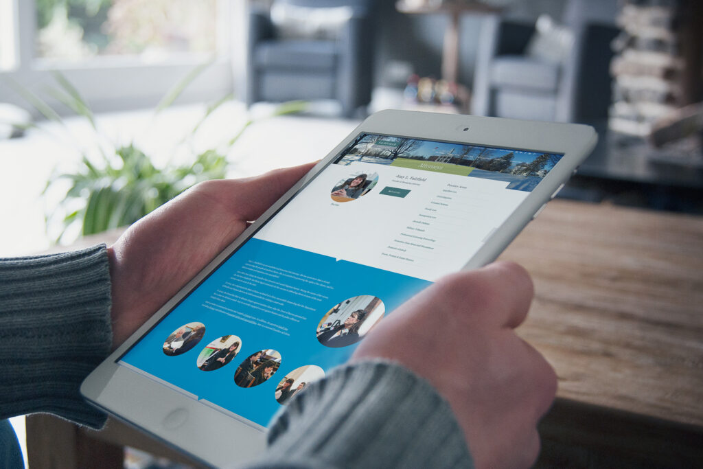 Attorney profile page on an iPad mini held in both hands, pairing the portrait and practice-area links with candid photography on a sea-blue panel.