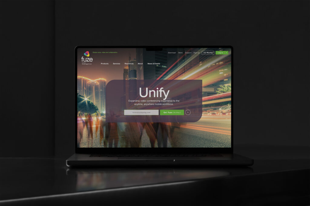Fuze homepage on a MacBook in the dark, the Unify hero glowing over long-exposure city motion with a Get Fuze signup.