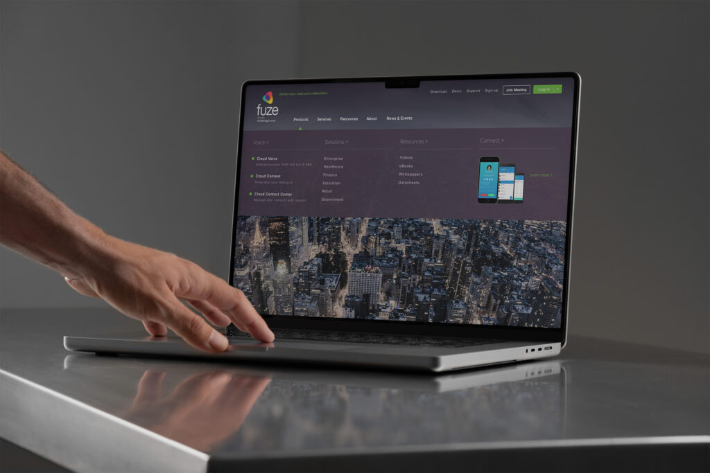 Fuze products mega menu open on a MacBook, Voice, Solutions, and Resources columns above an aerial Manhattan backdrop.
