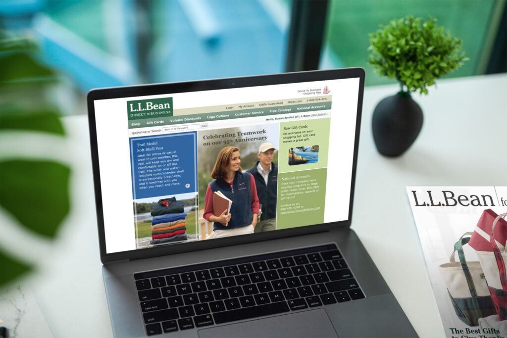 Laptop on a marble desk showing the Direct to Business homepage celebrating 95 years of teamwork, catalog cover at right.