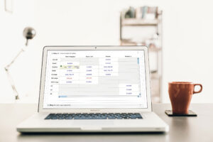 Laptop showing the step-two size and quantity ordering grid across regular, tall, misses, and womens columns, coffee mug alongside.