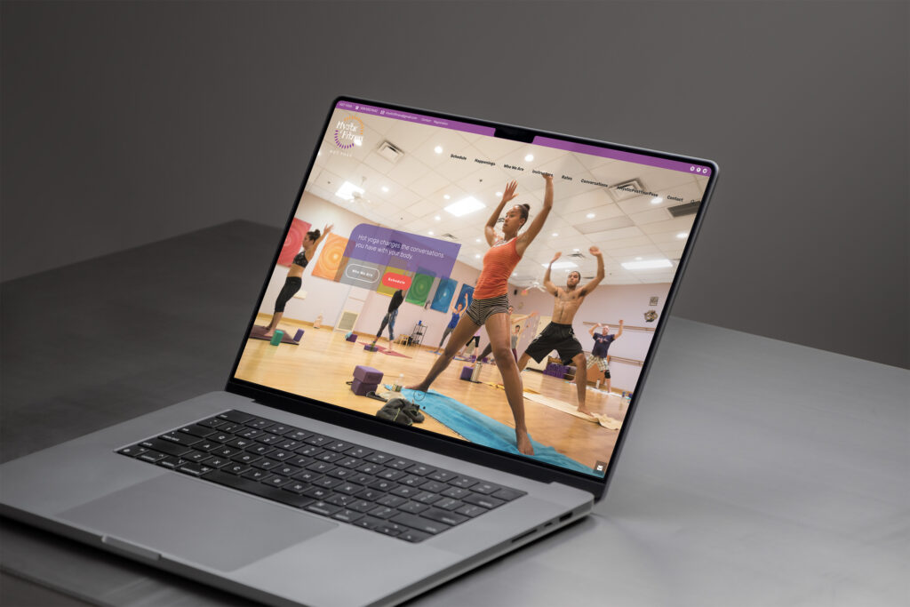 Mystic Fitness homepage on a MacBook Pro, its hero photo catching students mid-flow in a sunlit studio.