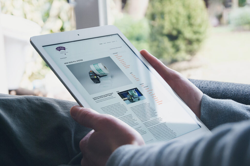 New Void-Fill System product page on an iPad, packaging rolls photographed above specifications and a demonstration video panel.