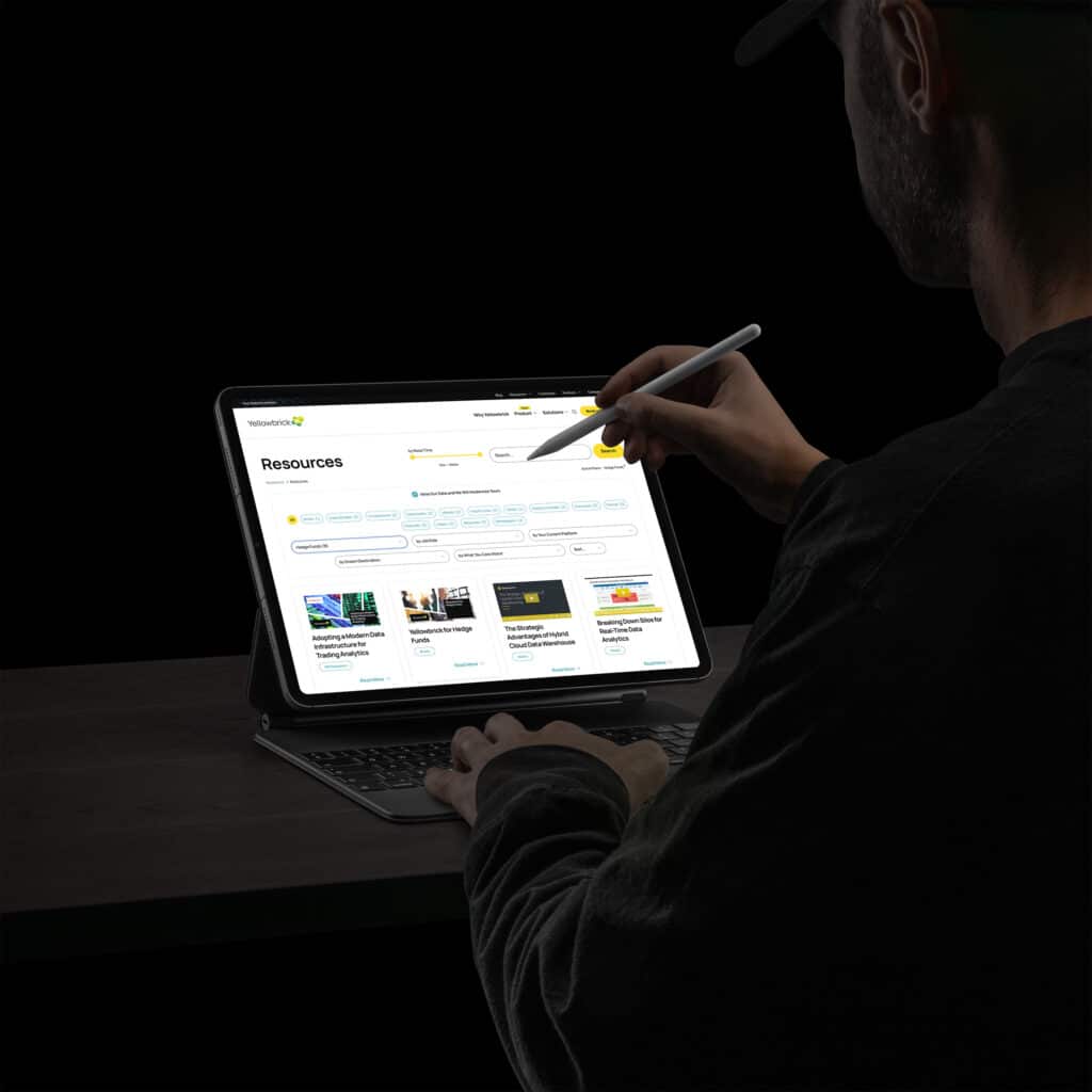 Man with a stylus filters the Resources library on a tablet, persona chips narrowing the whitepaper and brief cards.