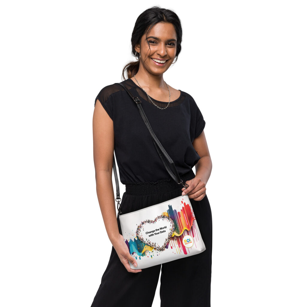 Smiling model holds the white crossbody bag forward, the crowd heart and brand promise printed across rainbow streaks.