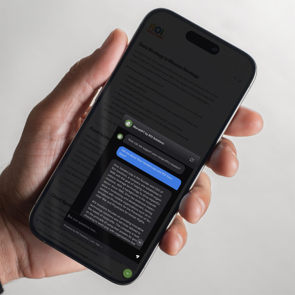 Hand holds a phone with the MariaGPT chat open over the mission strategy article, an answer streaming in.