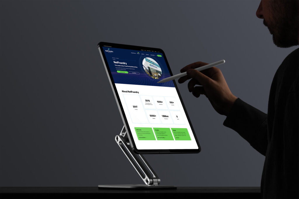 Silhouetted man with a stylus reviews the About page on a stand-mounted tablet, stat tiles glowing green below the hero.