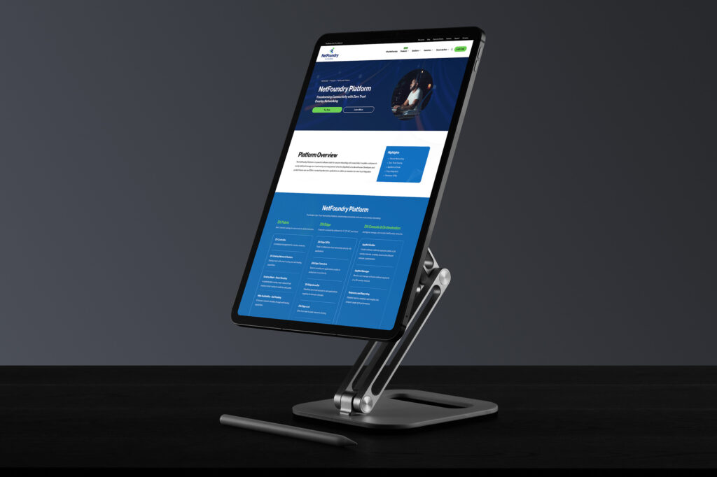 Stand-mounted tablet showing the NetFoundry Platform page, the overview panel above the blue capability grid.
