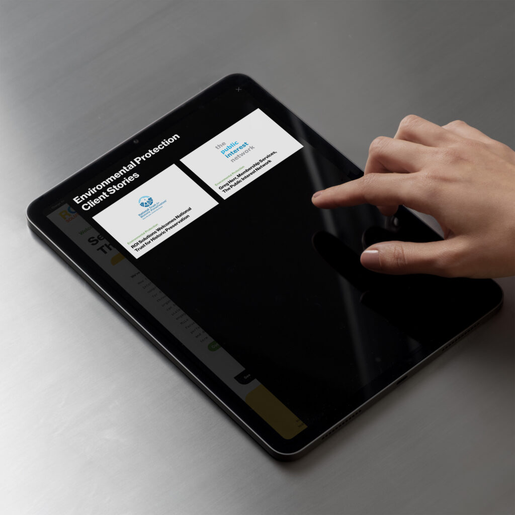 Finger scrolls a tablet showing environmental protection client stories, logo cards over the darkened landing page.