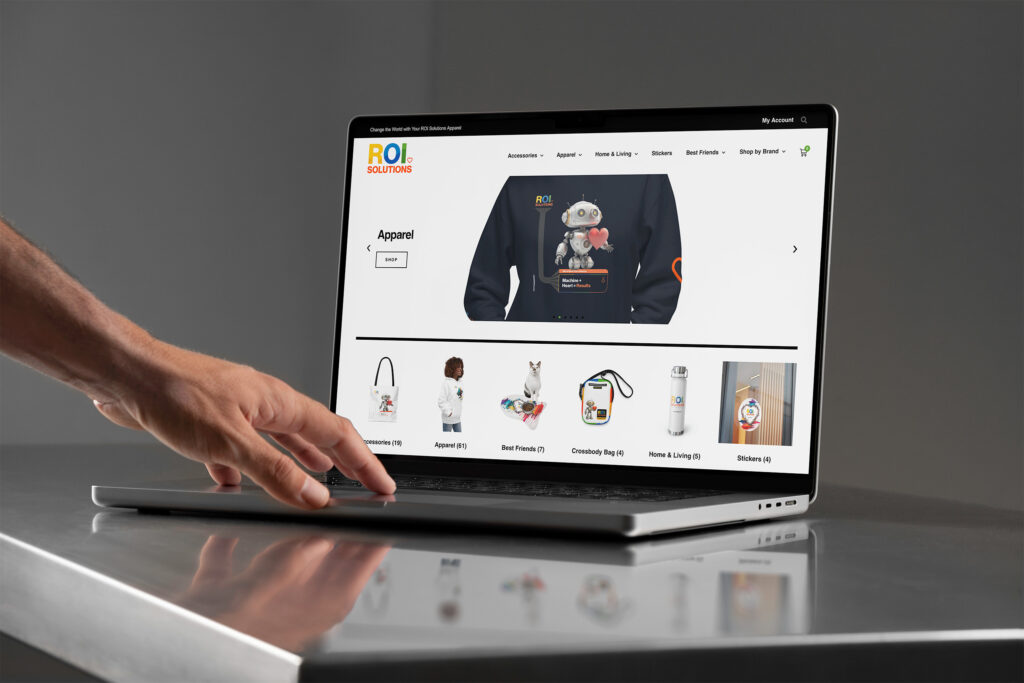 Hand scrolls the merch store apparel hero on a laptop, the MiLo hoodie above category tiles.