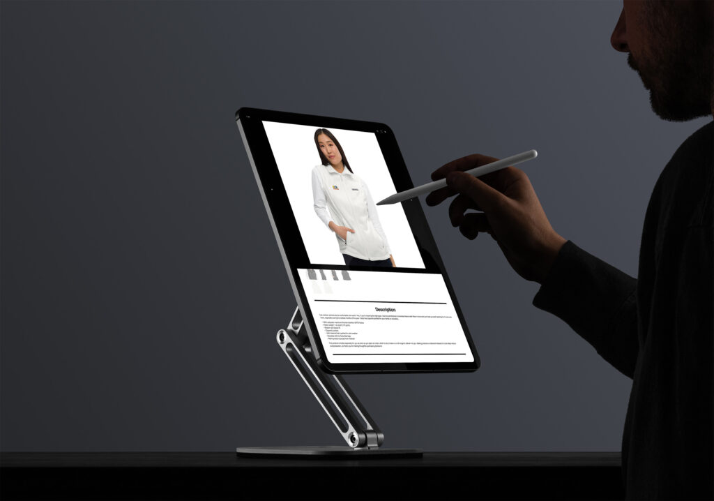 Stylus points at a fleece product page on a stand-mounted tablet in a dark studio.