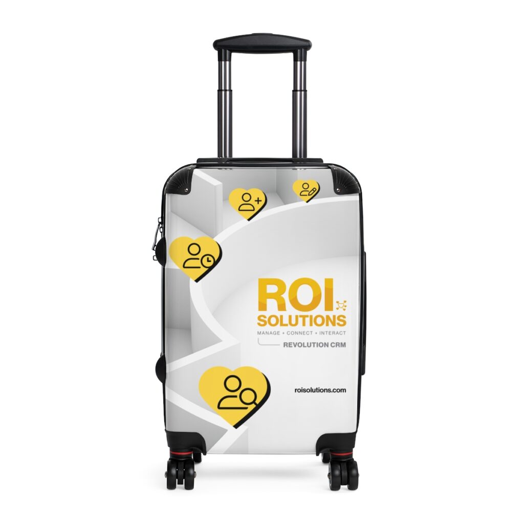 White carry-on spinner wrapped in the Revolution CRM identity, gold heart icons stepping across the maze pattern.