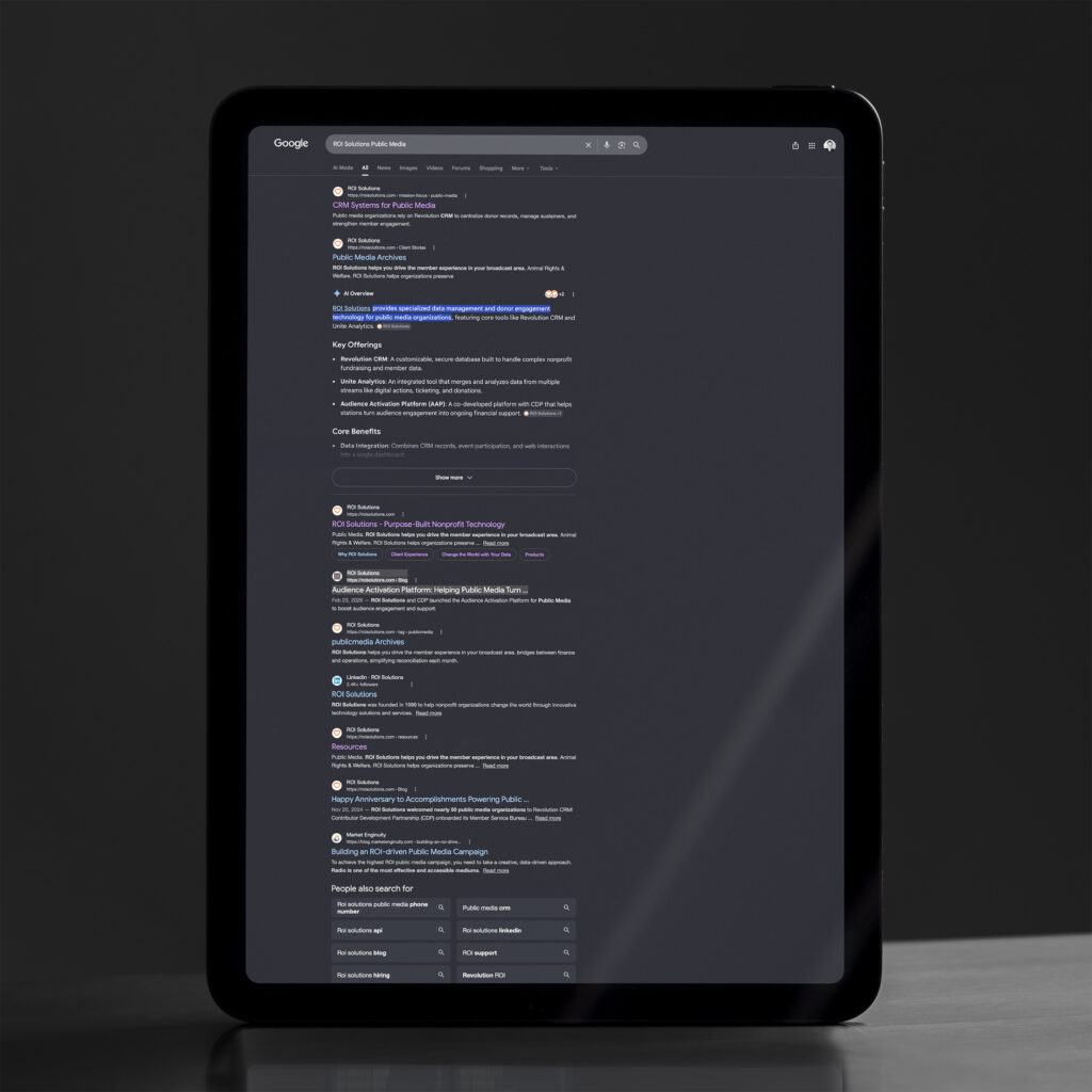Tablet showing branded Google results for ROI Solutions public media, an AI overview and site links filling the dark screen.