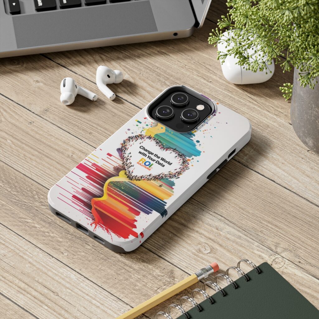 Cased phone lying on a wood desk beside earbuds and a laptop, the crowd heart print facing up.