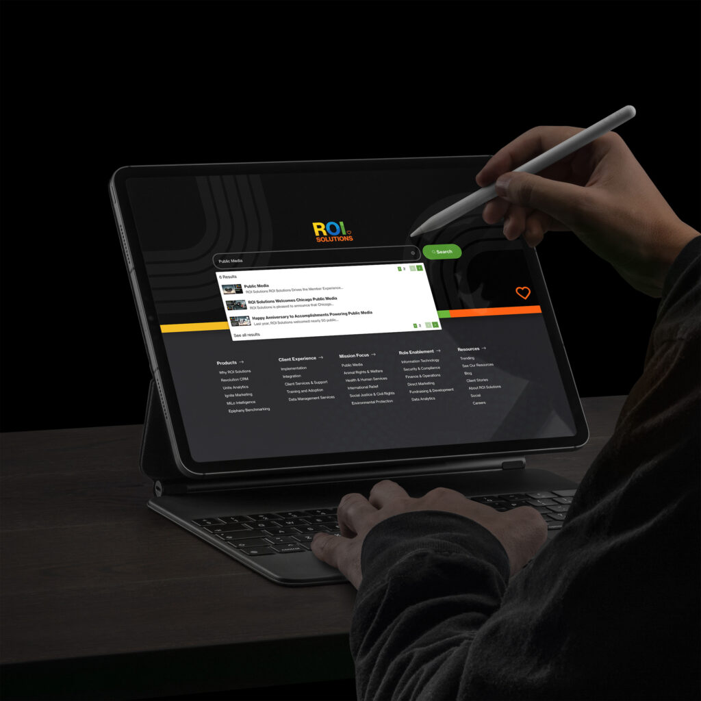 Stylus hovers over the dark site search overlay, public media results listed above the full navigation columns.