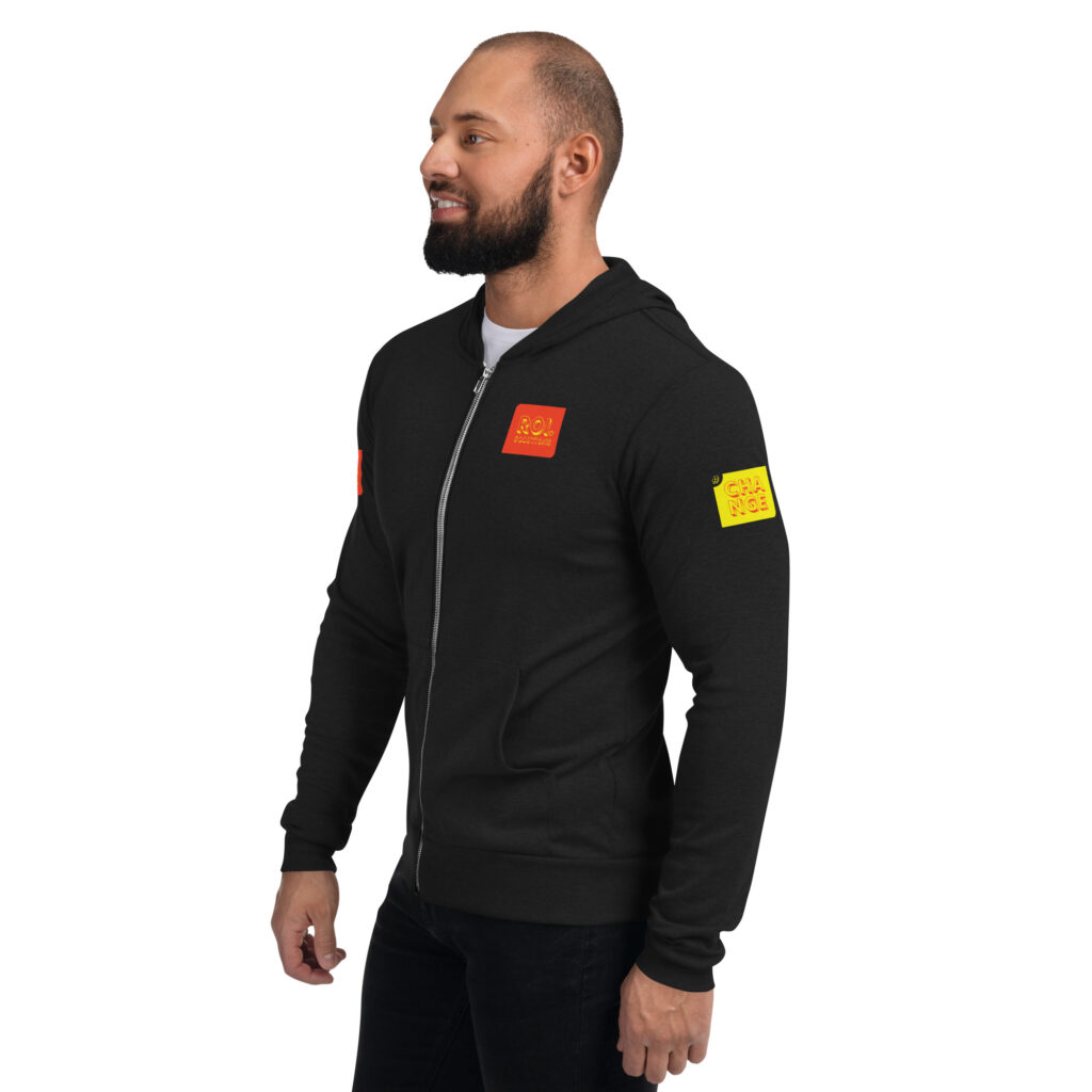 Side view of the solid black triblend hoodie, the gold sleeve patch and orange chest patch catching the light.