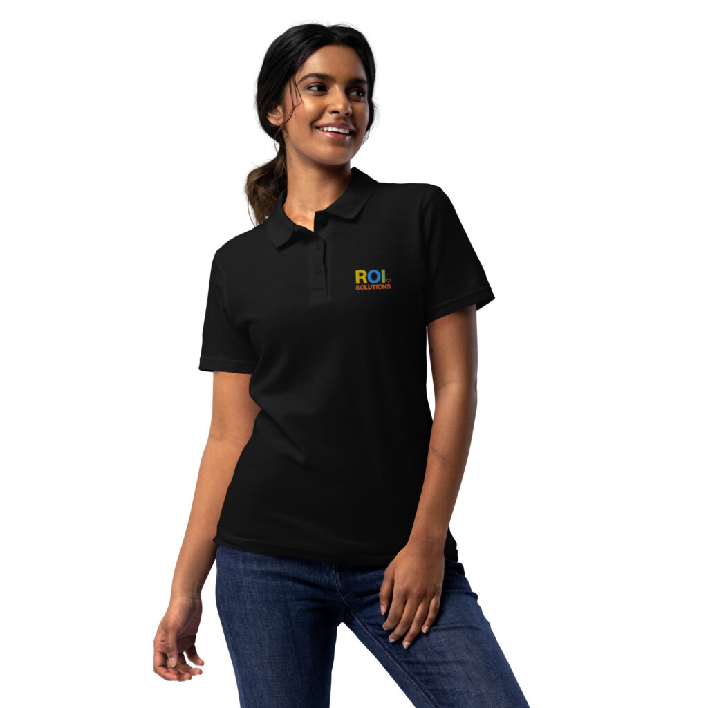 Model in the womens black pique polo shirt, the embroidered multicolor logo stitched at the chest.