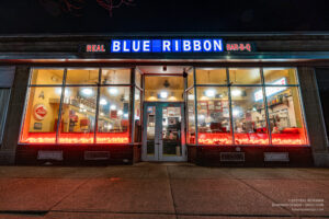 Real Blue Ribbon Bar-B-Q neon sign and lit storefront at night, Arlington MA.
