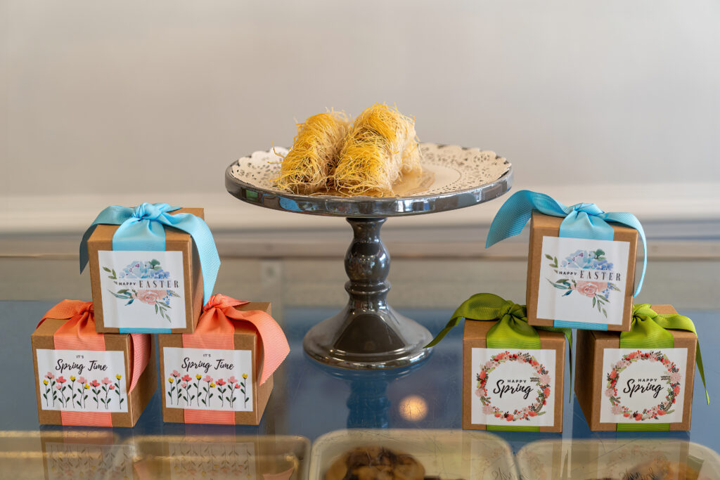 Kataifi pastries on a silver cake stand surrounded by ribboned Happy Easter and Spring gift boxes at Arlington Bakery.