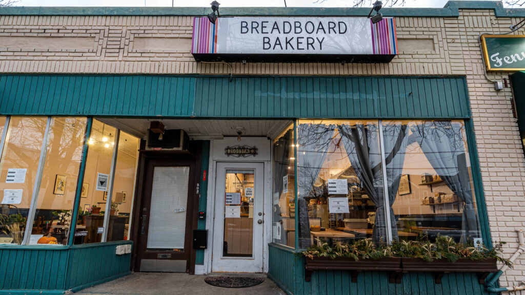 Breadboard Bakery storefront with teal wood trim, cream brick and a marquee-style sign, Arlington MA.