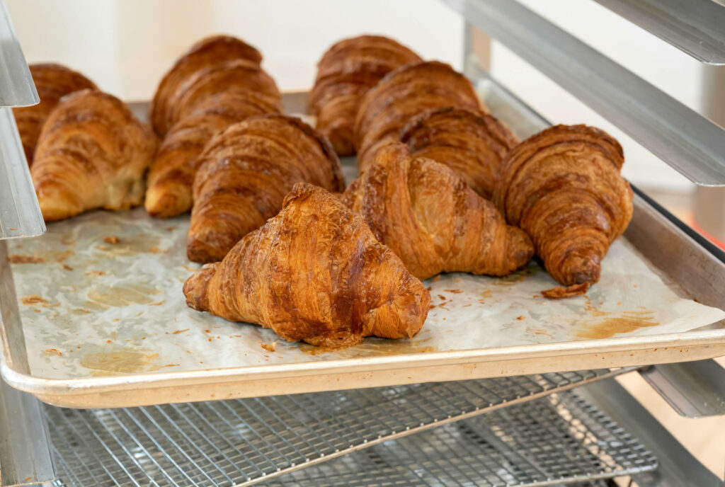 Freshly baked butter croissants on a sheet tray at Butternut Bakehouse.