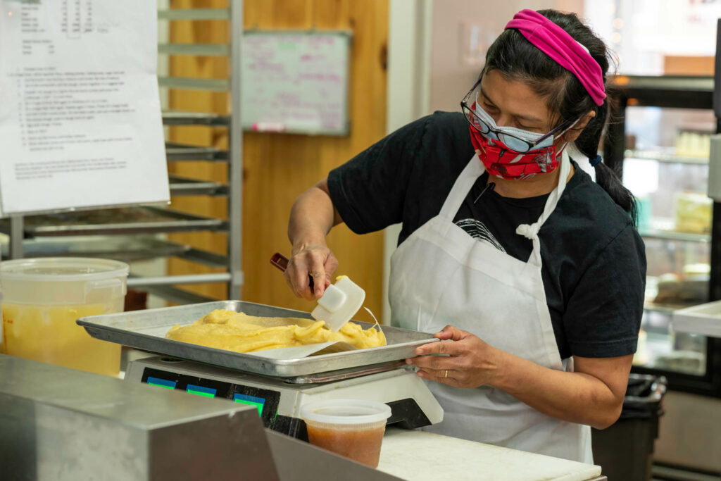 Owner Suzana Samad spreading filling on a sheet tray in the Butternut Bakehouse kitchen.