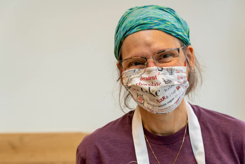 Butternut Bakehouse team member in a patterned head wrap, glasses and a bakery-print mask.