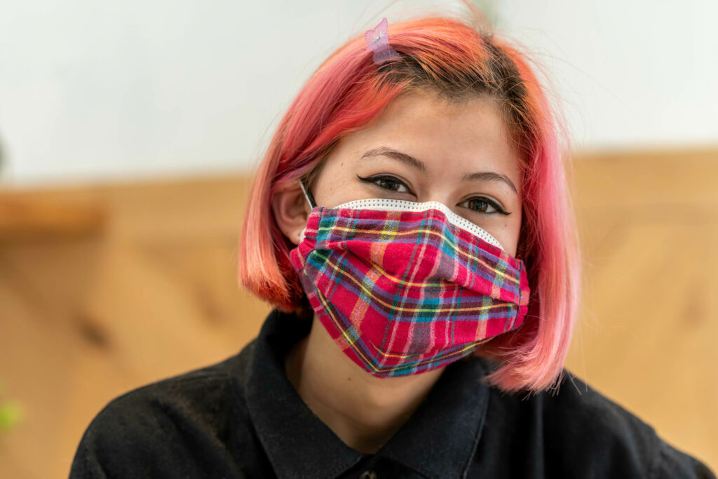 Butternut Bakehouse team member with pink hair in a plaid mask.