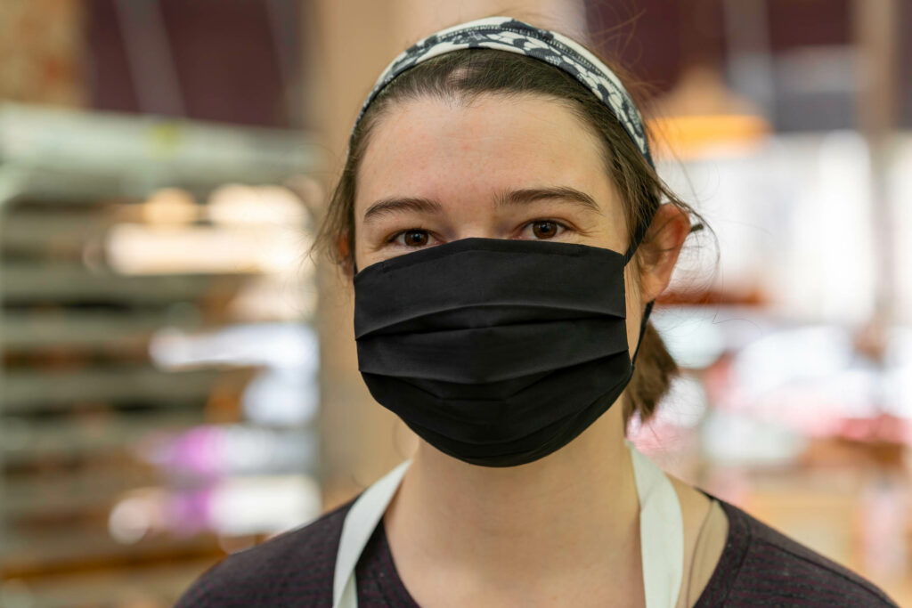 Butternut Bakehouse team member in a black mask and headband in the bakery.