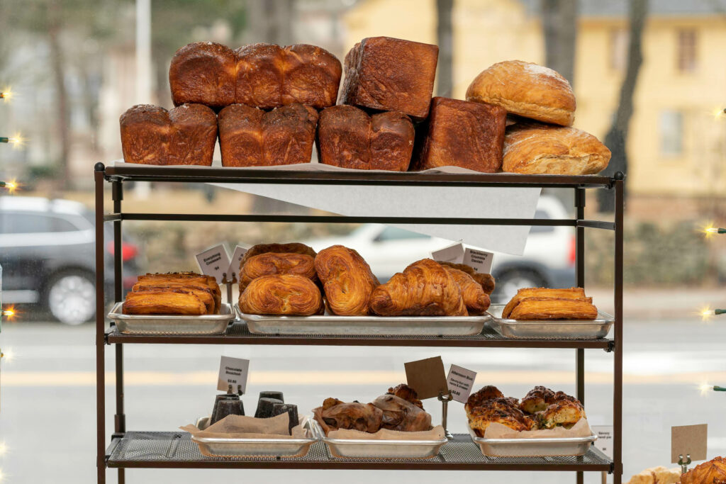 Tiered rack of brioche loaves, croissants and pastries in the Butternut Bakehouse window.
