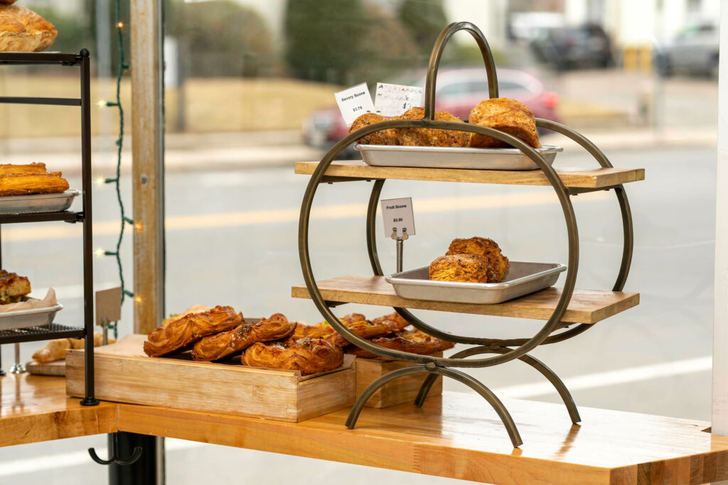 Pastries on a round iron display stand in the Butternut Bakehouse window with the street behind.
