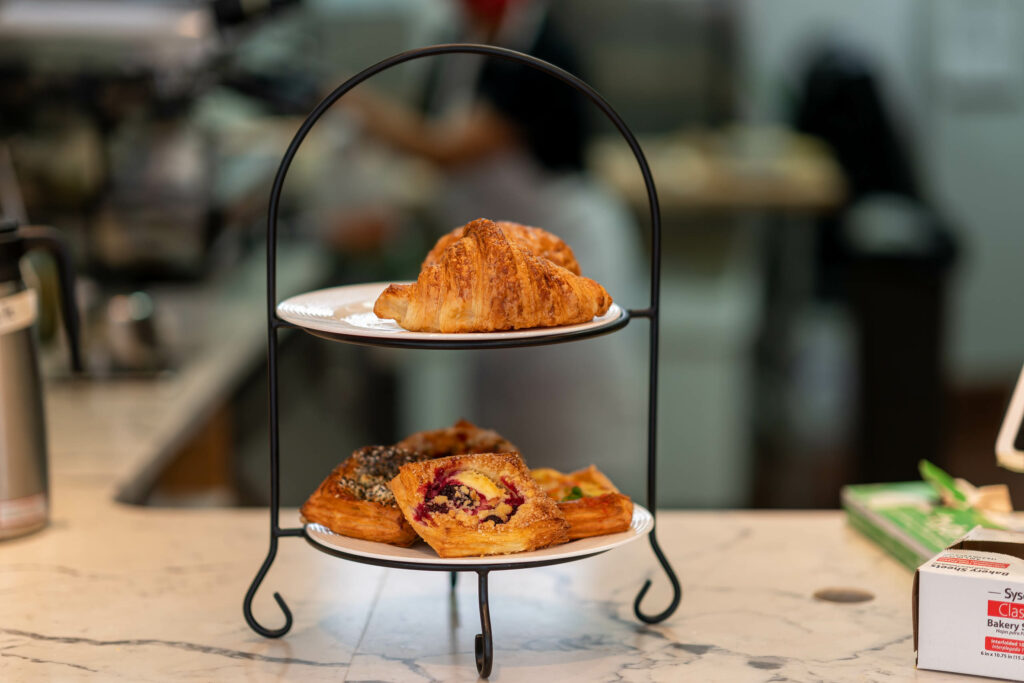 Two-tier stand holding a croissant and berry danish on the marble counter at Butternut Bakehouse.