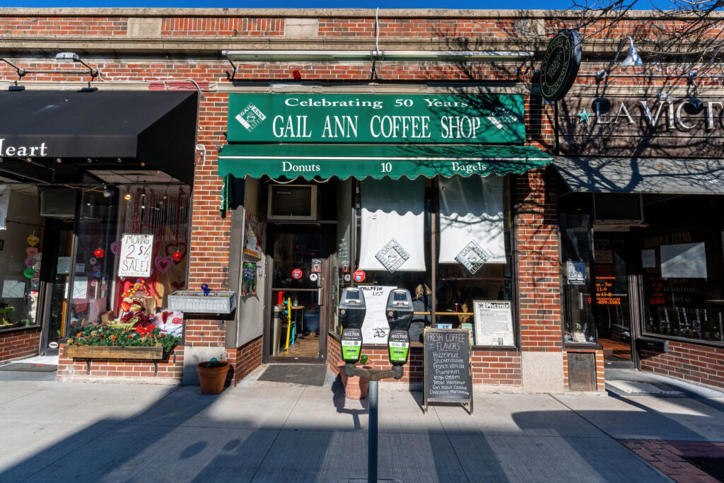 Gail Ann Coffee Shop brick storefront with green Celebrating 50 Years awning, donuts and bagels signs, Arlington MA.