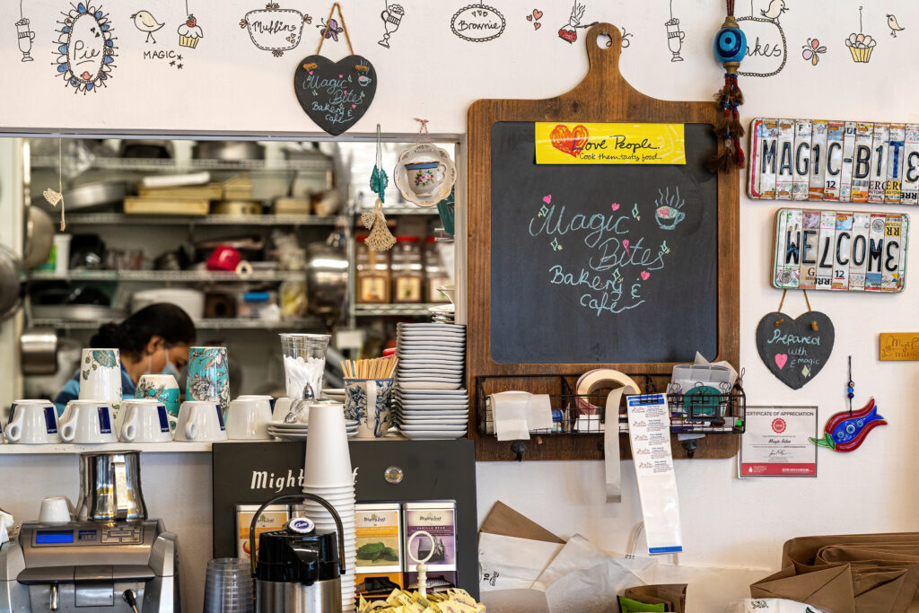 Magic Bites Bakery counter with chalkboard, Welcome sign made of license plates and coffee cups.