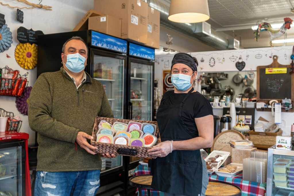 Elif and Atilla Ozkefeli holding a basket of decorated cookies inside Magic Bites Bakery.