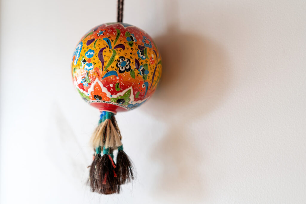 Hand-painted Turkish ceramic ornament with tassels hanging on a wall at Pasha's Little Grand Bazaar.