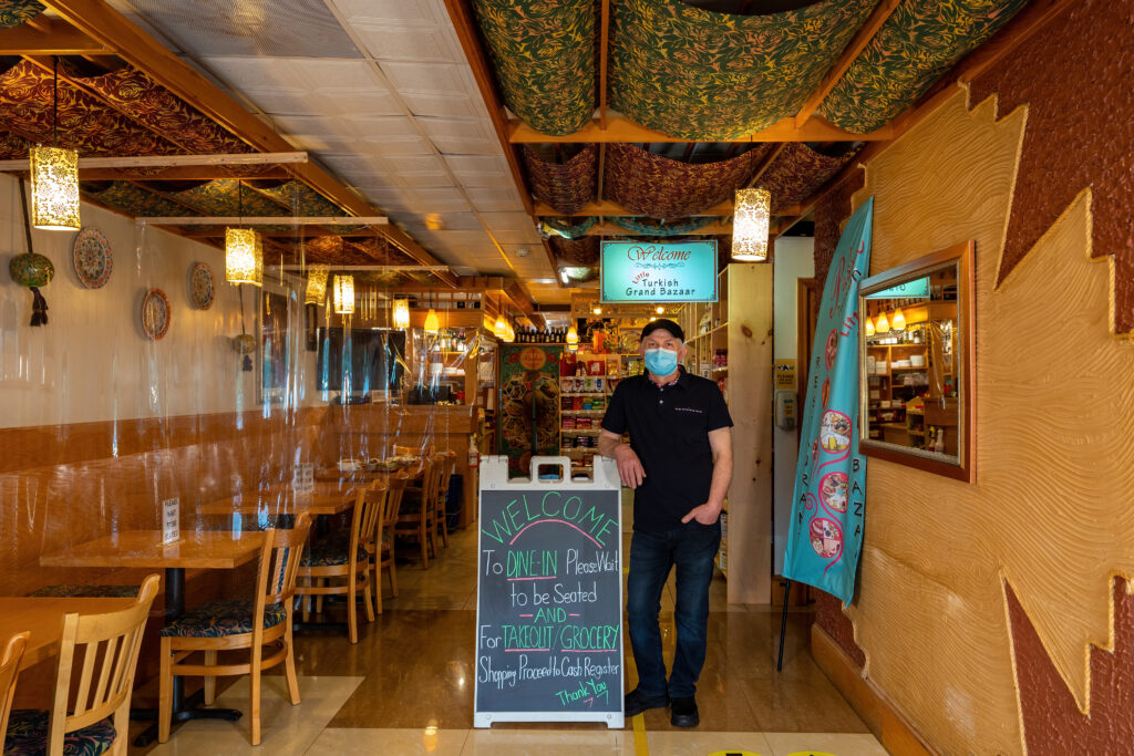 Owner Halit Candemir standing in Pasha's hand-built dining room beside the welcome board.