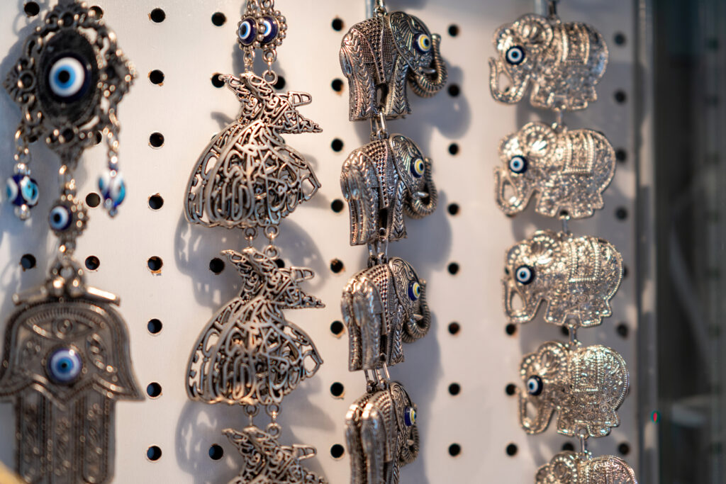 Silver elephant and hamsa charms with blue evil eye beads hanging in Pasha's Little Grand Bazaar.