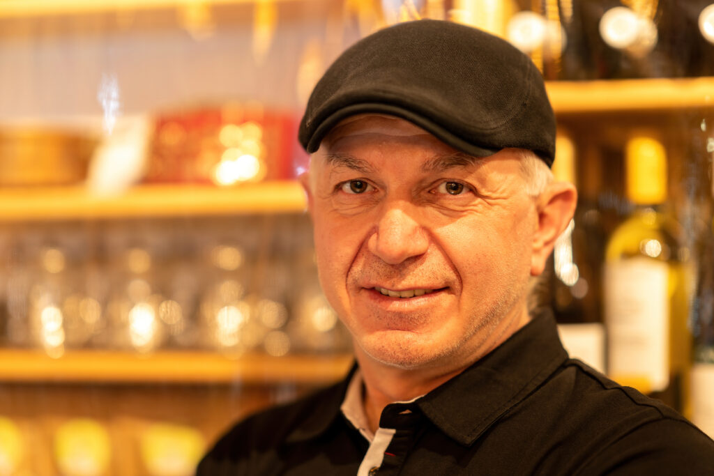 Close portrait of Halit Candemir, owner of Pasha, smiling in a flat cap.